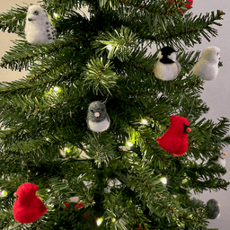 Close up of a small artificial Christmas tree with white lights. The tree's ornaments are all borbs: two snowy owls, one black-capped chickadee, two Northern cardinals, one dark-eyed junco. The cardinals are in the middle right and bottom left.