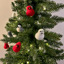 Close up of a small artificial Christmas tree with white lights. The tree's ornaments are all borbs: two snowy owls, one black-capped chickadee, three Northern cardinals, one dark-eyed junco. The Northern cardinals are in the top middle and lower left.