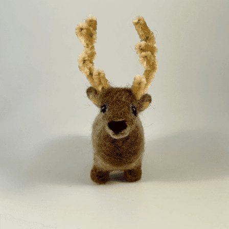 A needle-felted elk with pipe cleaner antlers faces directly towards the camera.