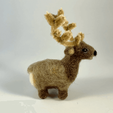 A needle-felted elk with pipe cleaner antlers faces towards the right.