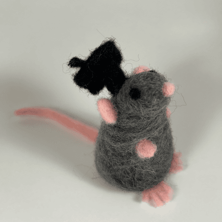 A grey rat with black eyes, pink nose, pink ears, pink paws and pink tail wearing a black graduation cap faces 1/4 right forward.