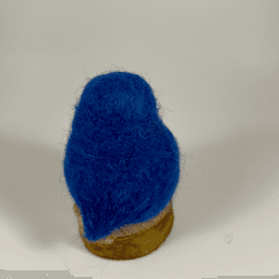 A needle-felted Eastern bluebird sits on a half inch section of a branch facing away from the camera. Its head, back, wings and tail are entirely royal blue.