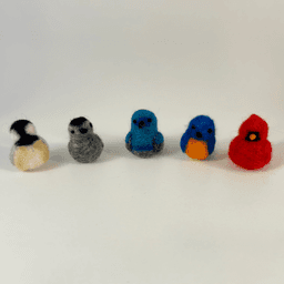 Five miniature needle felted borbs sit in a line facing the camera directly. From left to right, a black-capped chickadee, grey catbird, Palestine sunbird, Eastern bluebird, and Northern cardinal.