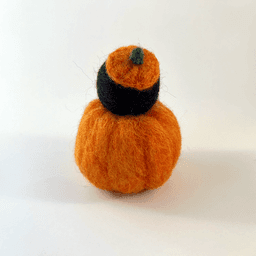 A needle felted black corvid borb pokes its head out of an orange pumpkin wearing a pumpkin stem hat. The borb faces away from the camera. Its eyes are lined in grey with a reflection.