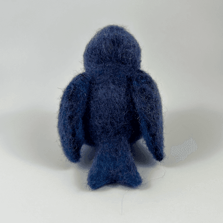 A needle-felted purple martin faces away from the camera.