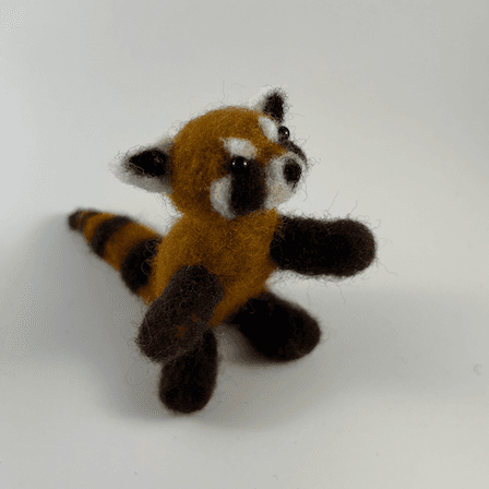 A needle-felted red panda sits up on its hind legs like red pandas do, facing 1/4 towards the right.