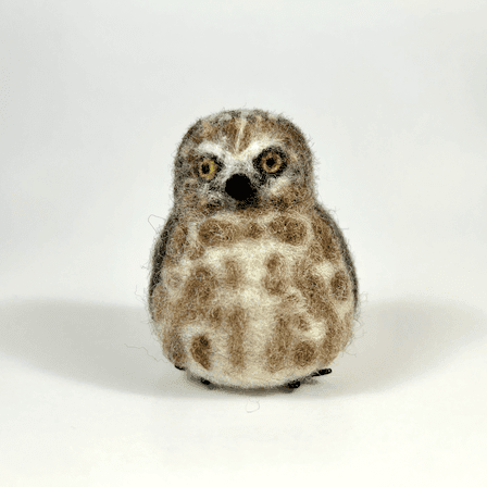 A needle-felted Northern saw-whet owl borb faces towards the camera.