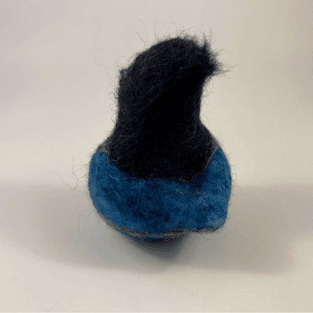 A needle-felted Steller's jay borb faces away from the camera 1/4 to the left.