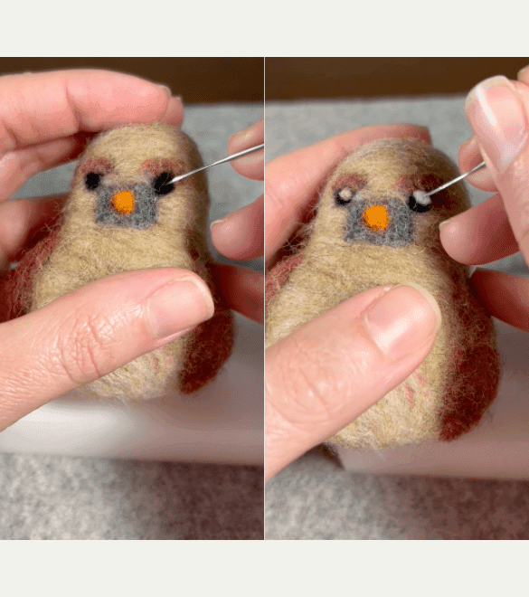 On the left side of the image, a partially obscured left hand holds a needle-felted female Northern cardinal while a mostly obscured right hand pokes in its right eye. The eyes are large black discs. On the right, the right hand adds a light colored crescent to the upper right corner of the right eye. A light colored crescent has already been added to the left eye.